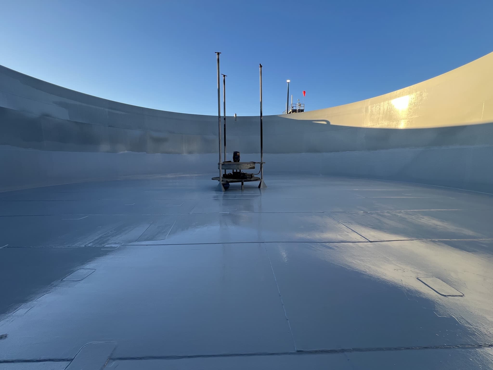 The interior floor and wall of a storage tank under a freshly applied grey lining